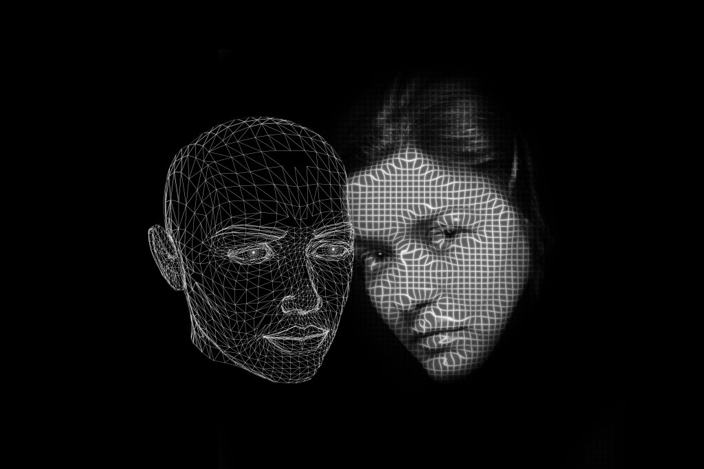 Black and white image of a womans face and a vector outline of a human head beside each other against a black background.